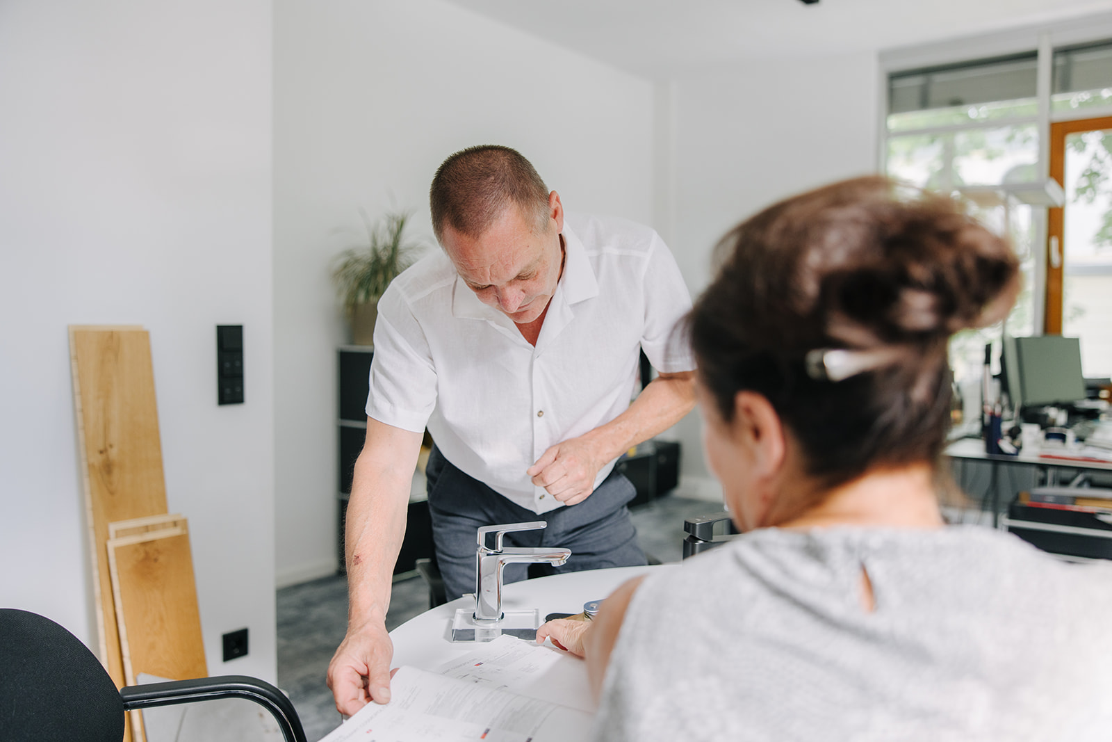 Haustechnik-Experte bespricht mit einer Kundin Planungsunterlagen und Armaturen für ein Sanitärprojekt.