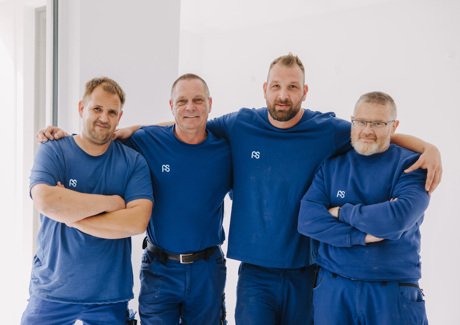 Vier Mitarbeiter von F+S Haustechnik im Teamfoto in blauer Arbeitskleidung.