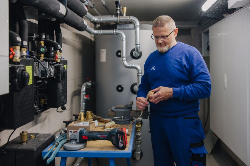 SHK-Monteur dichtet ein Gewindefitting für die Heizungsinstallation im Technikraum ab.